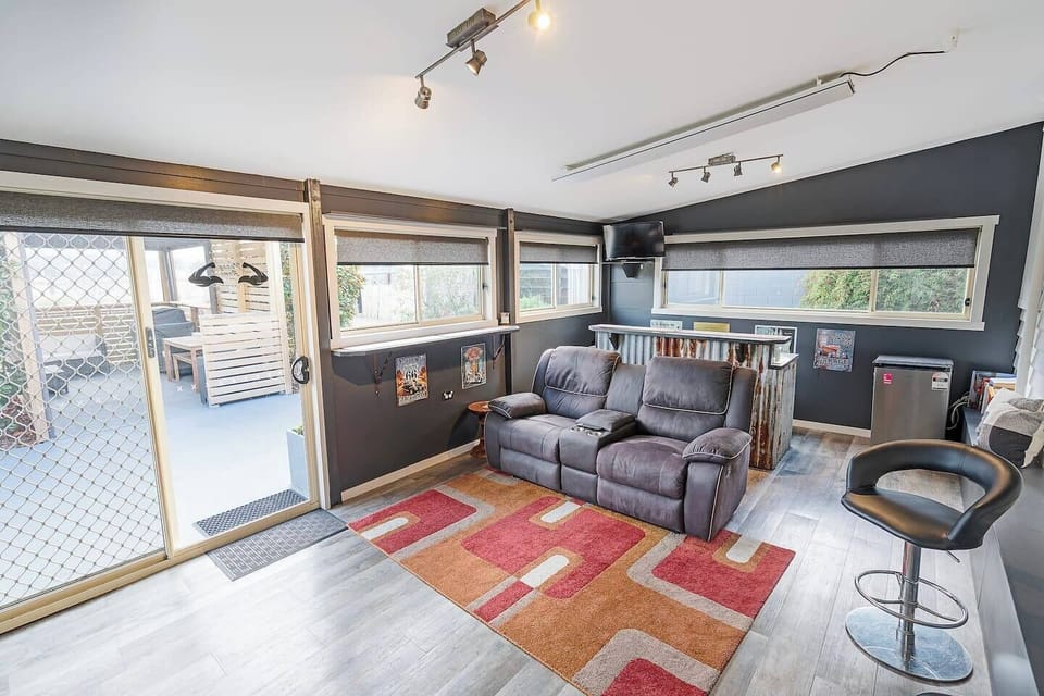 Venture downstairs to a den-style lounge with soft seating, two TVs, a rustic bar and mini fridge—ideal for sports nights, movie marathons or relaxed weekend drinks.