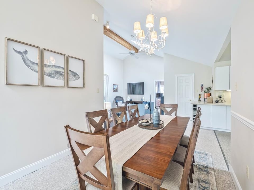 Spacious dining room with coastal-inspired artwork and a modern chandelier for a stylish group gathering space.