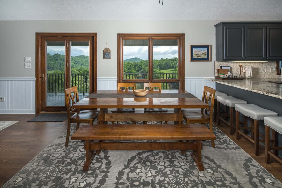 Dining area with seating for eight and mountain views just beyond the deck