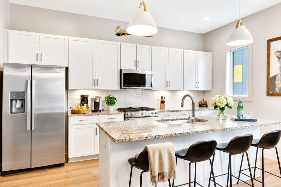 The granite island seats three at the bar while the stainless steel kitchen opens straight into the living room, so the cook stays part of the conversation