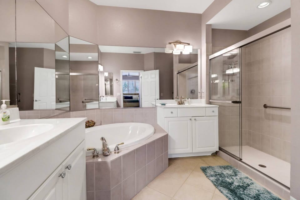The ensuite primary bathroom features dual sink vanities, a large walk-in shower, and corner soaking tub.
