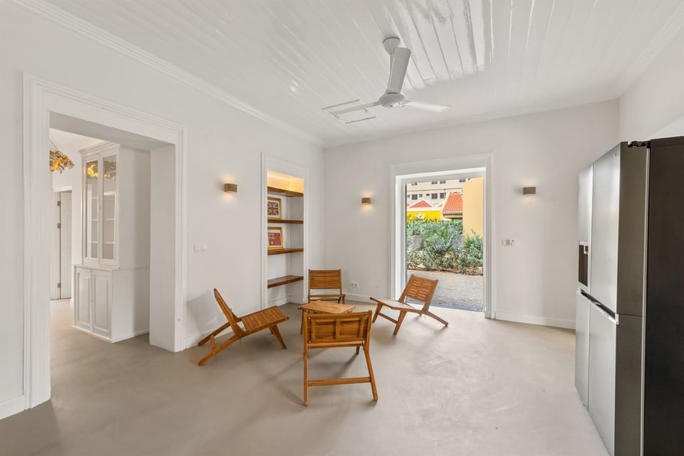 Bright kitchen-living space with a sleek countertop, designer lounge area, and French shutter doors opening onto the side terrace ideal for breezy indoor-outdoor living in Otrobanda, Curaçao.