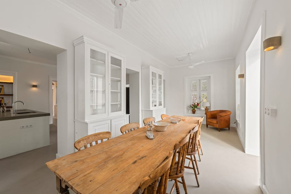 Charming dining room in Villa Grandi, Curaçao, with high ceilings, shuttered windows, and an elegant wooden table a unique, atmospheric space that blends colonial character with Caribbean style. Perfect for shared meals and memorable moments.