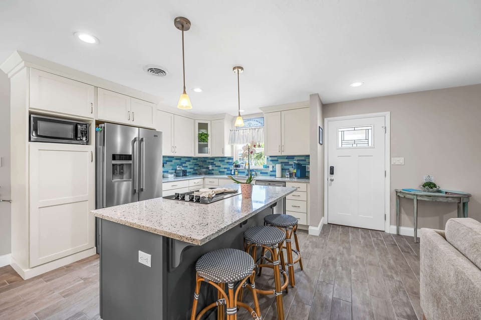 Modern kitchen with a large island and blue tile backsplash for family-friendly gatherings.