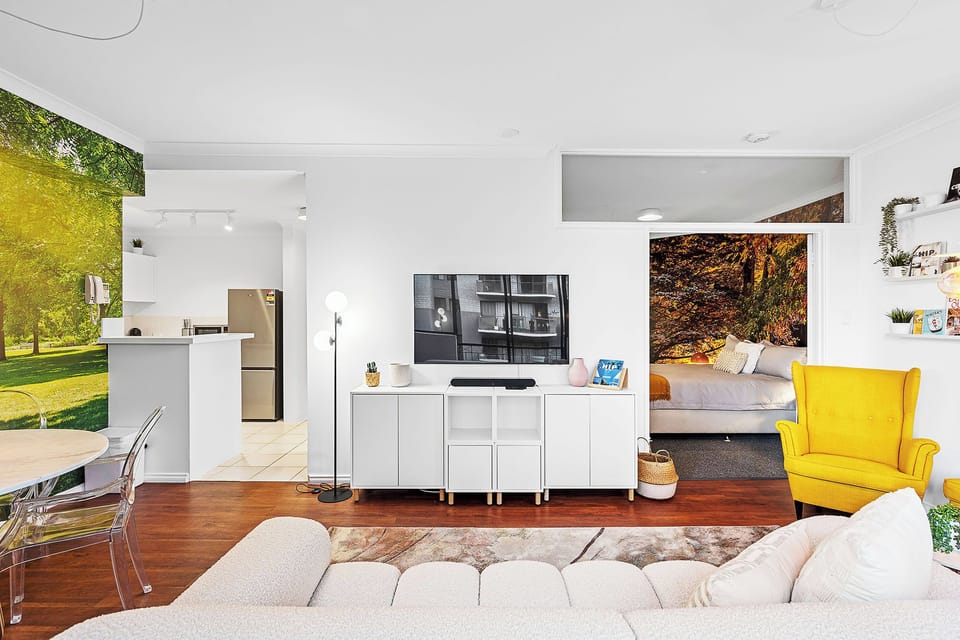 Discover a vibrant and comfortable living space with modern amenities, and a cheerful yellow accent chair, seamlessly connecting the kitchen and sleeping area for an inviting stay.