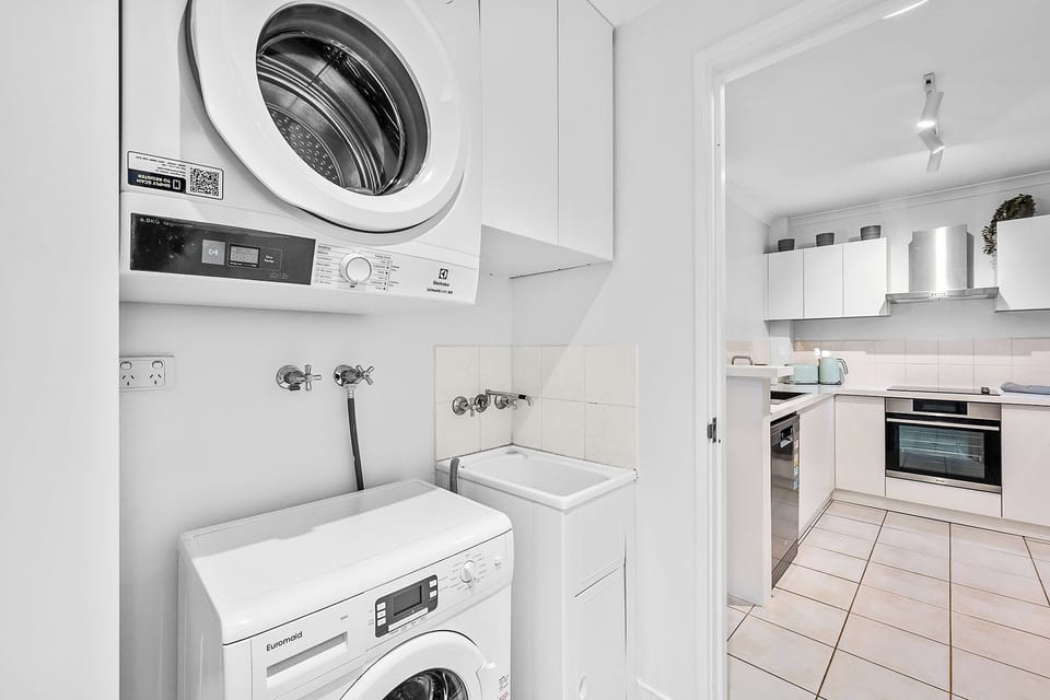 Discover the convenience of a bright and efficient laundry area, complete with a modern washing machine and dryer, designed for ease and functionality within a pristine white setting.
