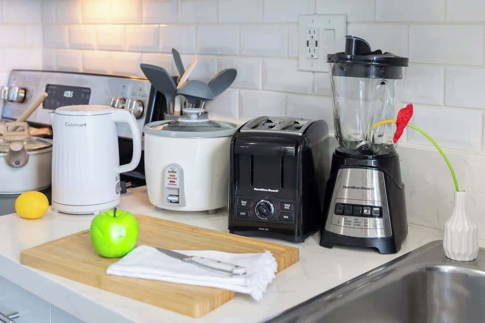 Whip up delicious meals and snacks with ease, thanks to a well-equipped kitchen featuring essential appliances like a Cuisinart electric kettle, rice cooker, Hamilton Beach toaster, and a versatile blender.