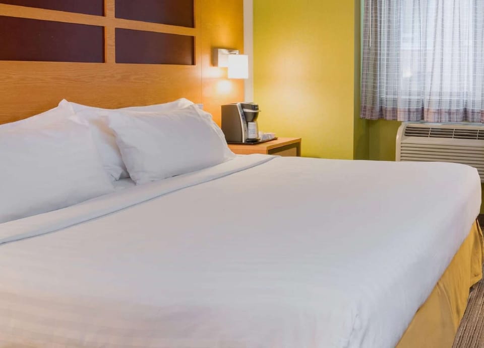 King bed with coffee maker by window and yellow accent wall