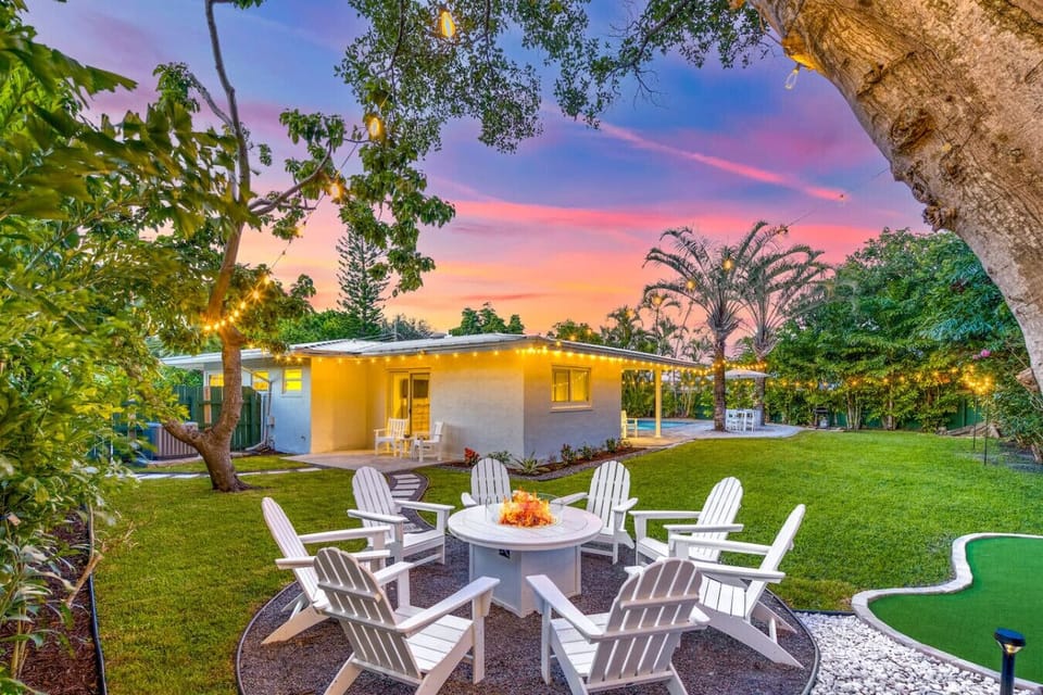 Settle in around the fire pit as twilight sets the scene—string lights frame the spacious backyard, with custom mini golf and room to roam beneath the glowing banyan tree.