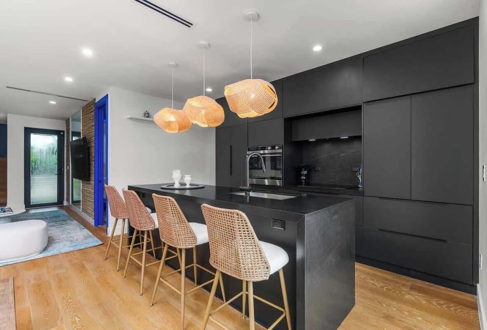 With a spacious island and comfortable bar stools, this gourmet kitchen is a perfect spot for morning coffee or casual conversation. The sleek, dark cabinets and unique lighting add a touch of sophistication.
