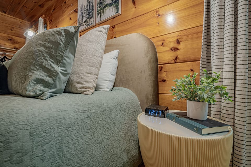 This cozy bedside area offers a thoughtful touch with a digital alarm clock, a good book, and a touch of greenery, providing all the comforts for a peaceful night's rest. It's perfectly designed for unwinding after a day of adventures.