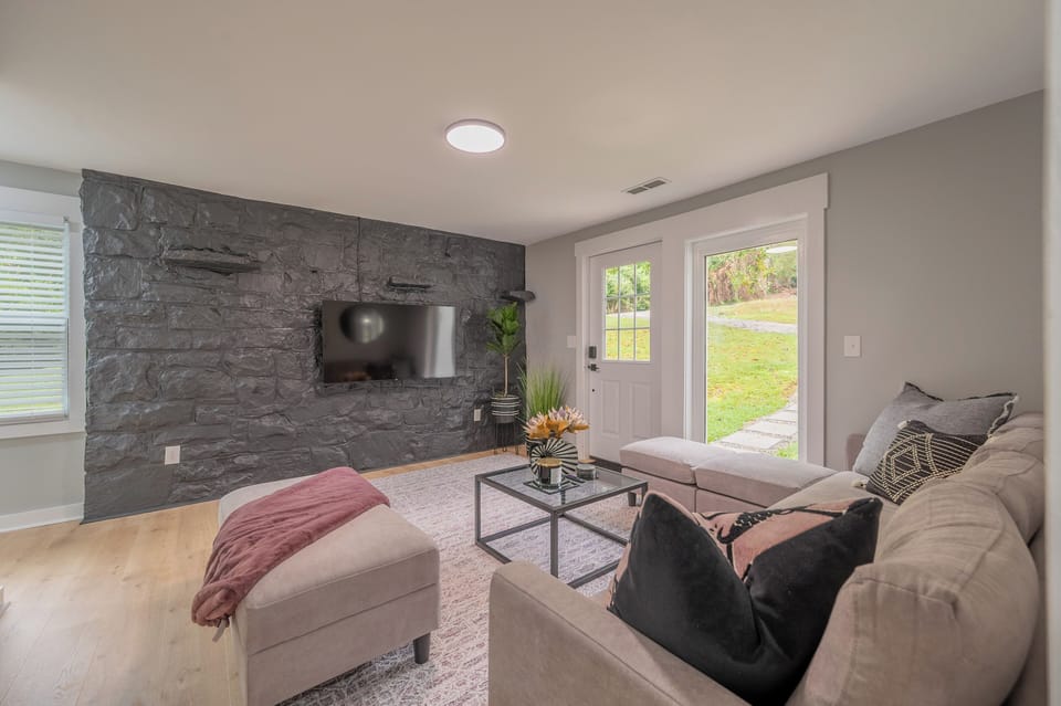 Cozy living room with a stone accent wall, large windows, and smart TV for relaxing nights in.