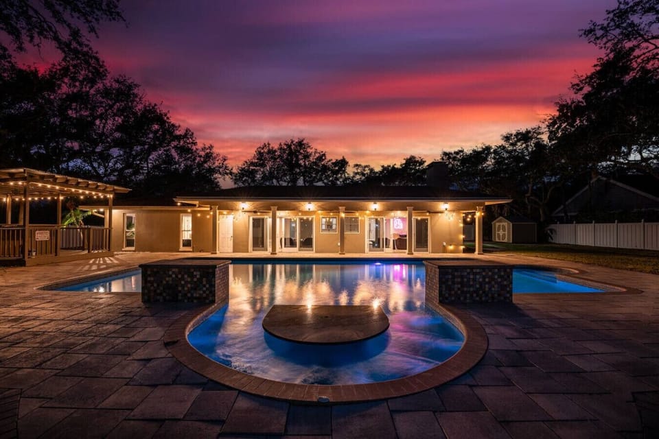 Relax and unwind in this stunning backyard oasis. Enjoy the tranquil pool surrounded by twinkling lights, with a breathtaking sunset sky to set the perfect mood.