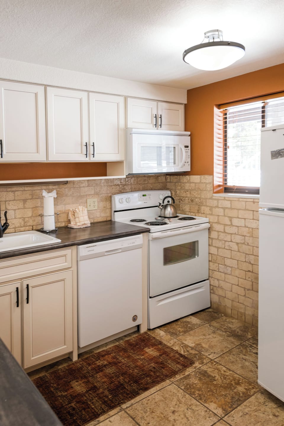 Your fully equipped kitchen awaits with white appliances, warm brick backsplash, and everything you need to prepare meals during your stay.