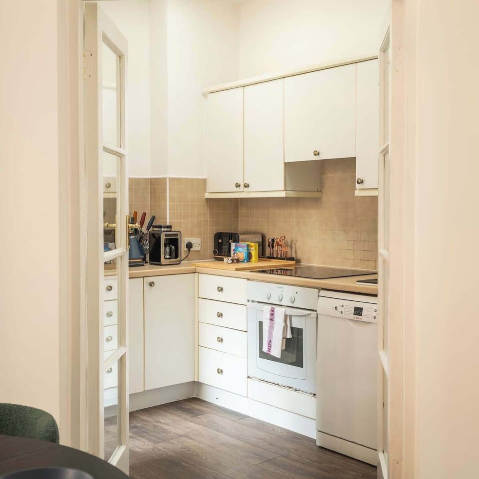 Kitchen with induction hob, oven, microwave, pots & pans, toaster, coffee maker, dishwasher, fridge and kettle.