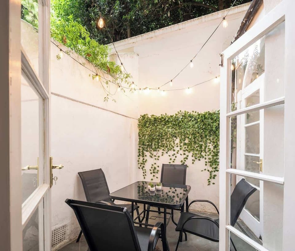 Outdoor patio area with table, chairs and overhead lights.