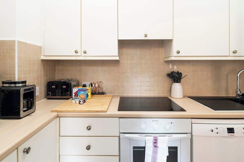Kitchen with induction hob, oven, microwave, pots & pans, toaster, coffee maker, dishwasher, fridge and kettle.