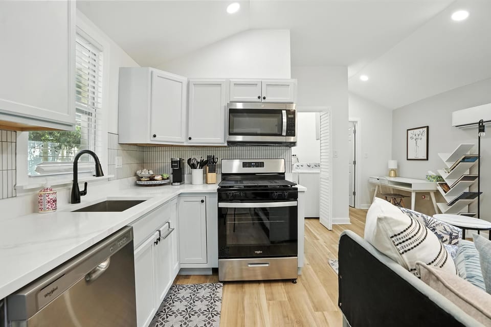 Modern kitchen with stainless steel appliances, gas stove, microwave, dishwasher, and full-size fridge—perfect for cooking meals during your stay. Enjoy a bright, open space that flows into the living and work areas for easy family gatherings.
