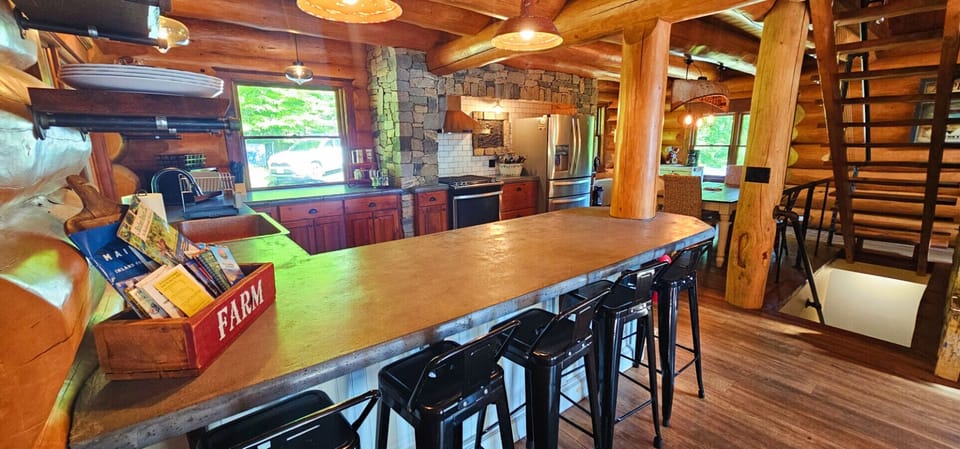 Rustic log cabin kitchen with a spacious island, stone accents, and seating for gathering together.