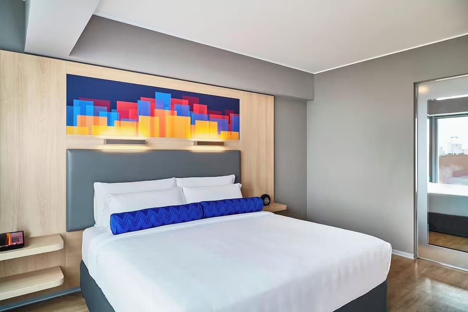Unwind in crisp linens beneath bold, modern headboard art.