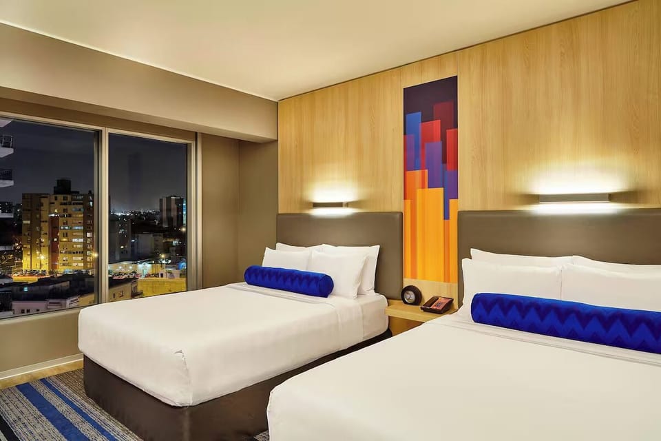 End the day with cozy beds and a glowing skyline backdrop.