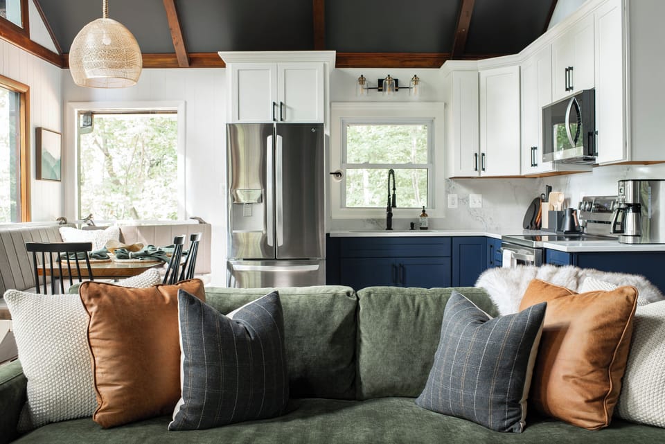 Start your morning with coffee at the breakfast nook, where forest views and natural light set a peaceful tone. The fully-stocked kitchen flows into to the dining area and living room, where guests can connect in comfort.