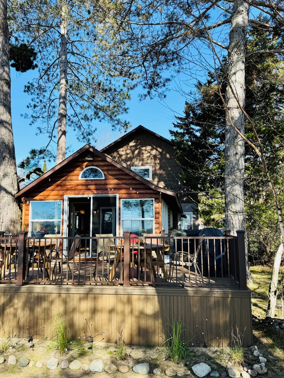 This large lakeside deck has a Blackstone, a gas grill, two tables and chairs.