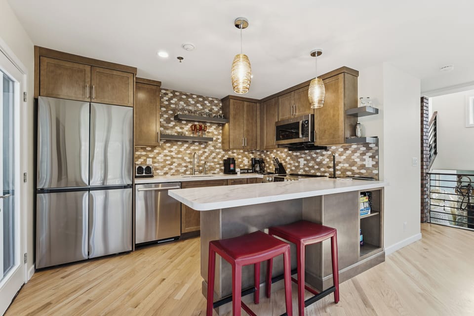 Modern, fully equipped kitchen with stainless steel appliances, ample counter space, and a breakfast bar with seating—ideal for preparing meals and gathering with family or friends.