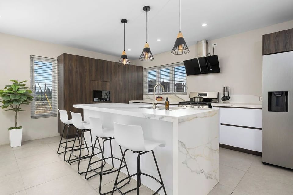 Modern chef’s kitchen with island, bar seating, stainless steel appliances, and wood cabinetry, plenty of space to cook, gather, and enjoy meals with family or friends.