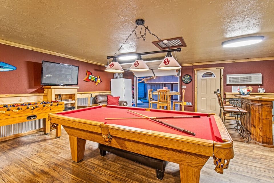 Garage game room with pool table, foosball, cornhole, and bar area