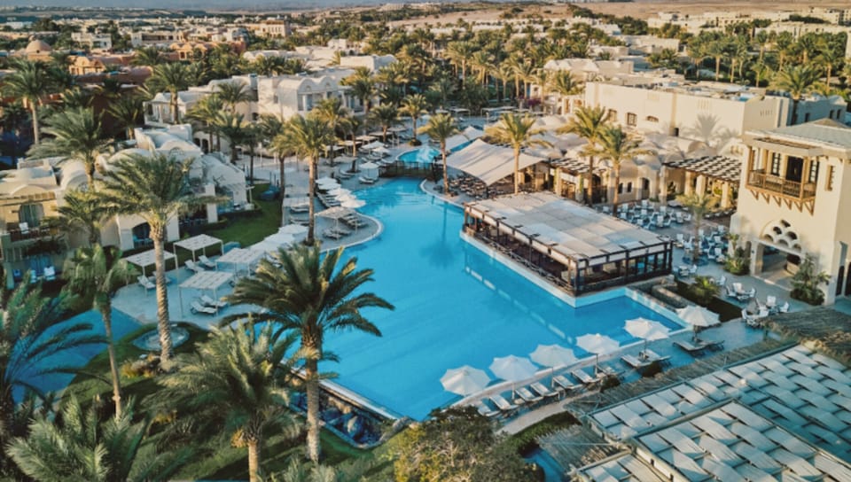 Take in the expansive pool scene framed by palms and cabanas.