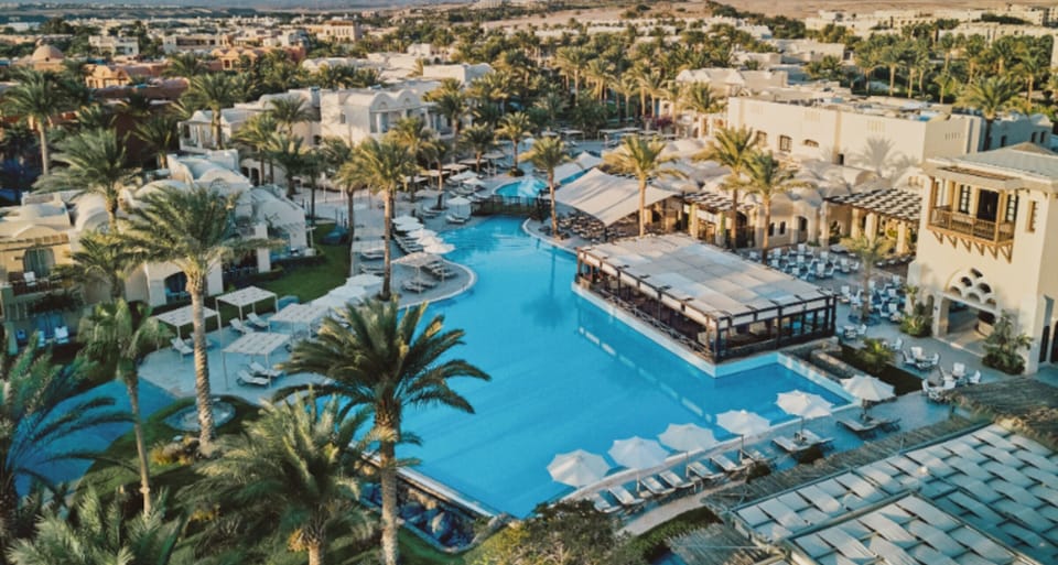 Take in the expansive pool scene framed by palms and cabanas.