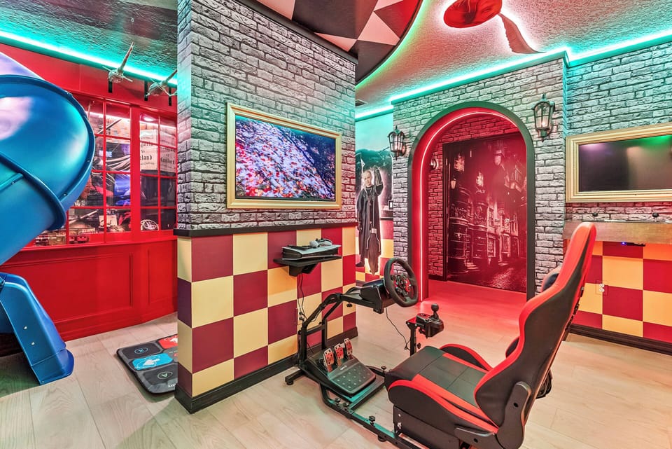 Experience our vibrant game room with bold red and black decor, checkered walls, and neon lights that create an energetic vibe. Settle into our comfy gaming chairs for fun-filled evenings and unforgettable moments.