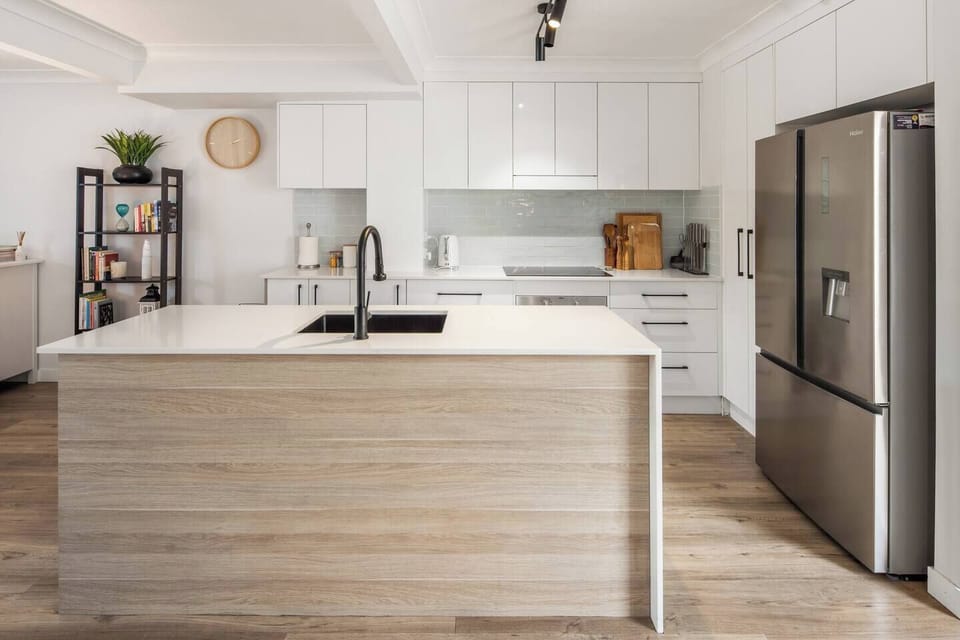 A spacious central island offers plenty of prep space and casual seating, setting the stage for morning coffees, shared platters, or evening drinks.