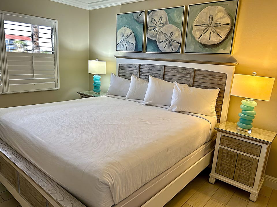 Unwind in a sunlit king bed with coastal artwork.