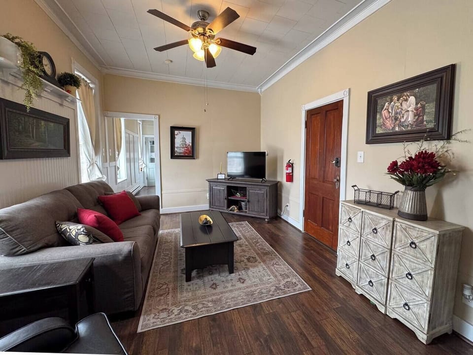 Inviting living room with a gray sofa, patterned rug, and a view extending into another area.