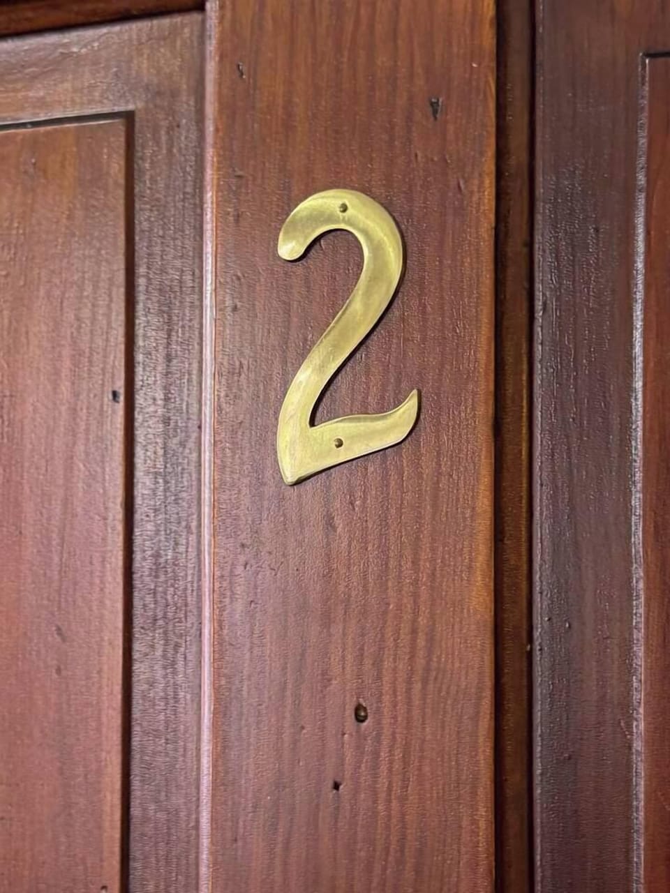 Close-up of a wooden door with a gold number "2".