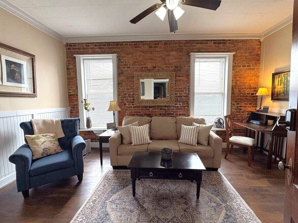 Cozy living room with exposed brick, comfortable seating, and natural light.