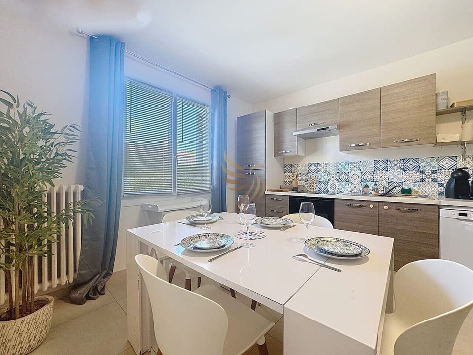 Une cuisine moderne et équipée et son coin repas avec une grande table et 4 chaises.