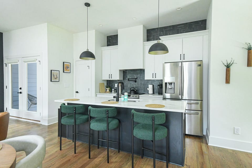 Chef’s kitchen with bar seating and moody green velvet stools for a pop of luxury.