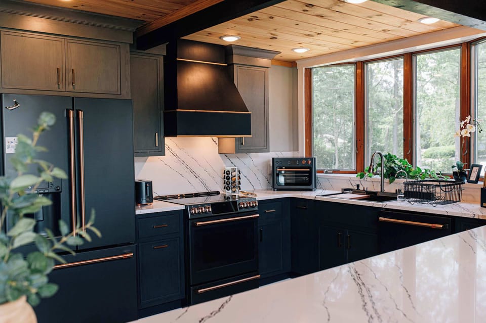 A chef’s dream: modern black sink, luxe gold knives, and a view of the trees as your backdrop.
