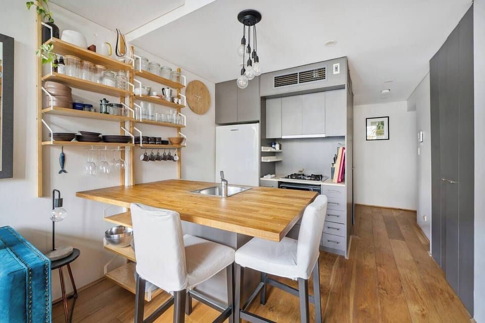 \Enjoy the modern yet homey atmosphere of the kitchen and dining zone, perfect for casual meals at the timber dining table surrounded by floating shelves.