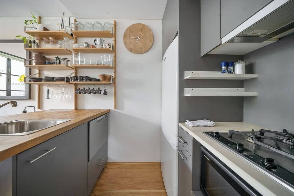 	The compact kitchen’s sleek design invites you to prepare meals with ease, especially with modern appliances offering convenience within arm’s reach.
