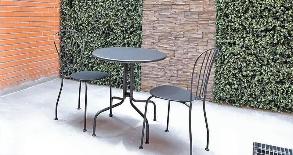 Private terrace w/ café table seating set beside a lush green wall