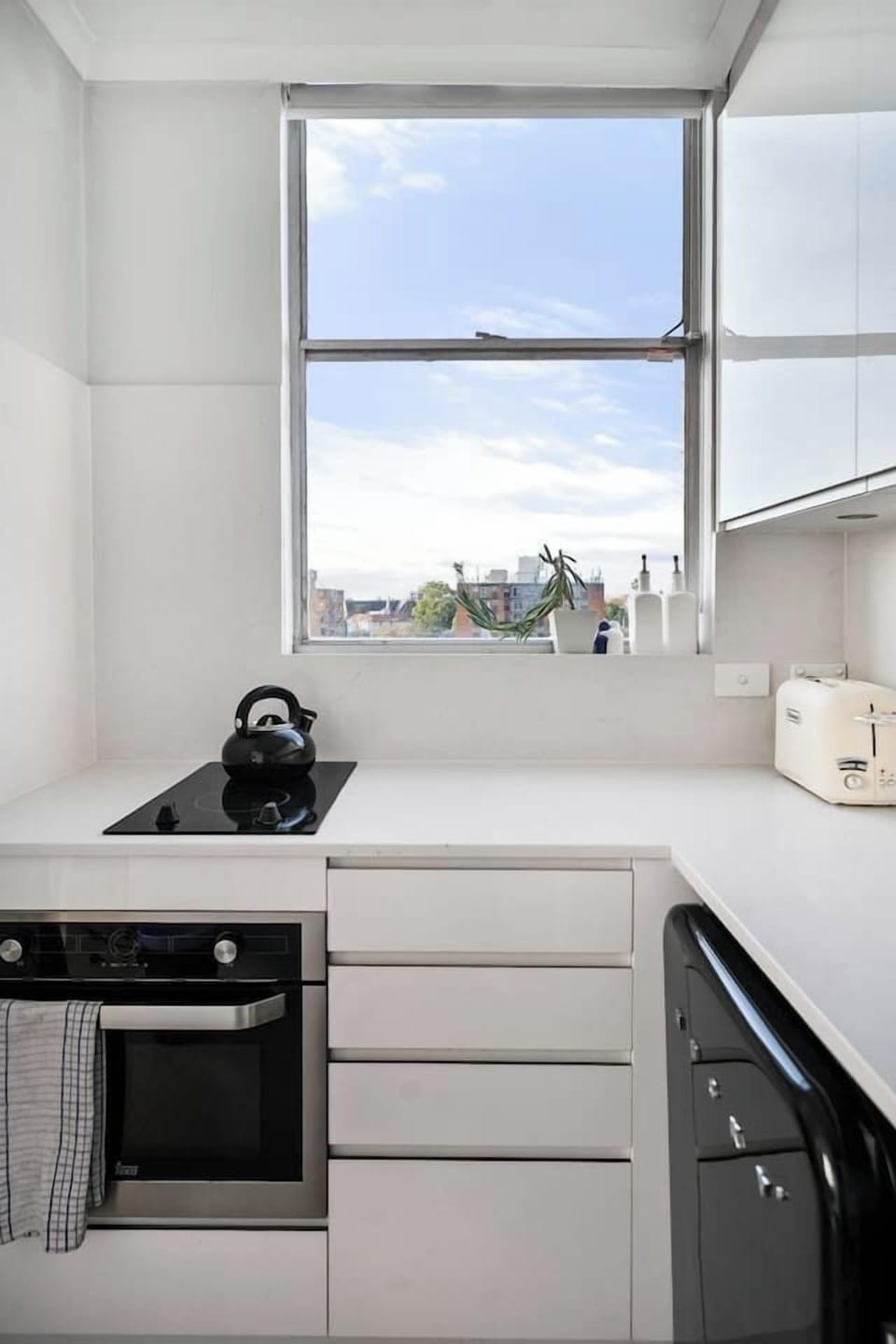 Prepare fresh market finds in a streamlined kitchen that blends style and practicality with a dishwasher, oven, cooktop, mini fridge and modern fittings.