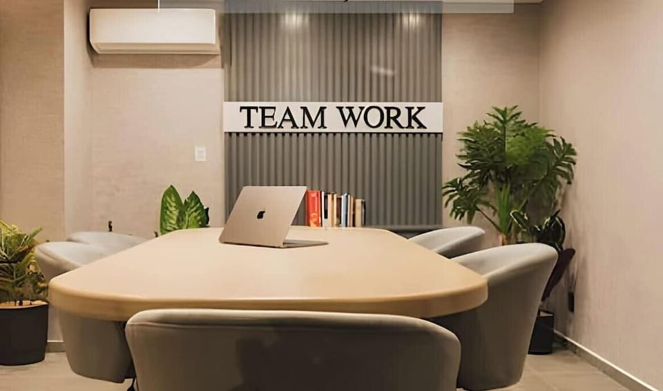 Round table workspace w/ comfy chairs & “Team Work” wall art for casual meetings or meals