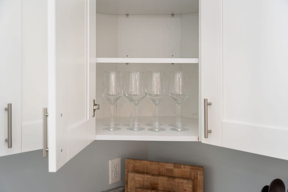 Clear wine glasses are neatly arranged in an open kitchen cabinet.
