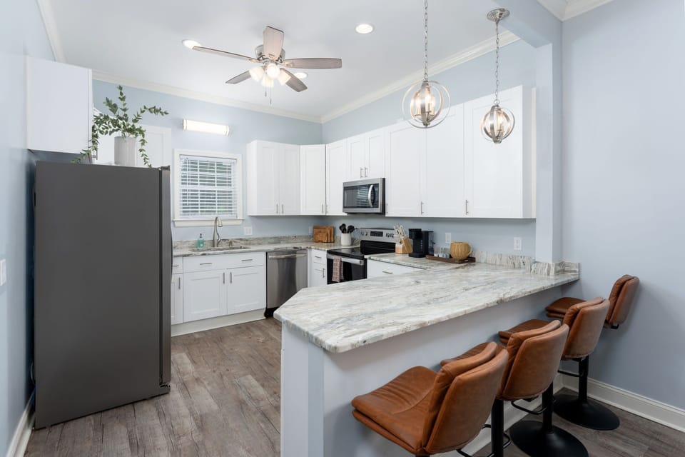 Kitchen island with granite countertop and brown leather bar stools.