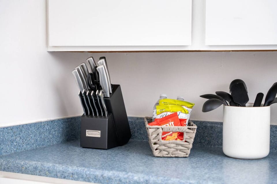 Kitchen countertop with a knife block, snacks, and cooking utensils.