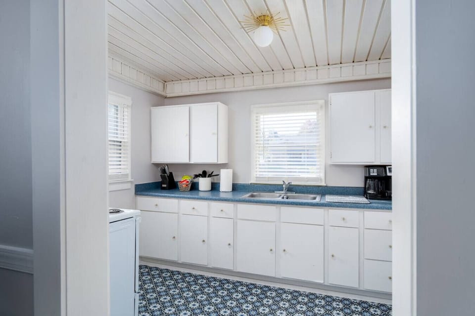 Bright kitchen with white cabinets, blue countertops, and patterned floor tiles.